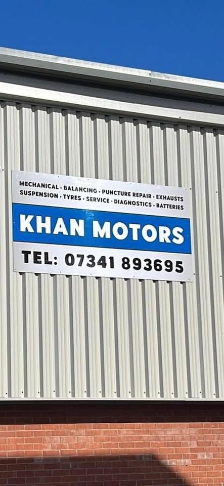 The Khan Motors sign on the unit against a blue sky, with the services line above the name and the phone number below